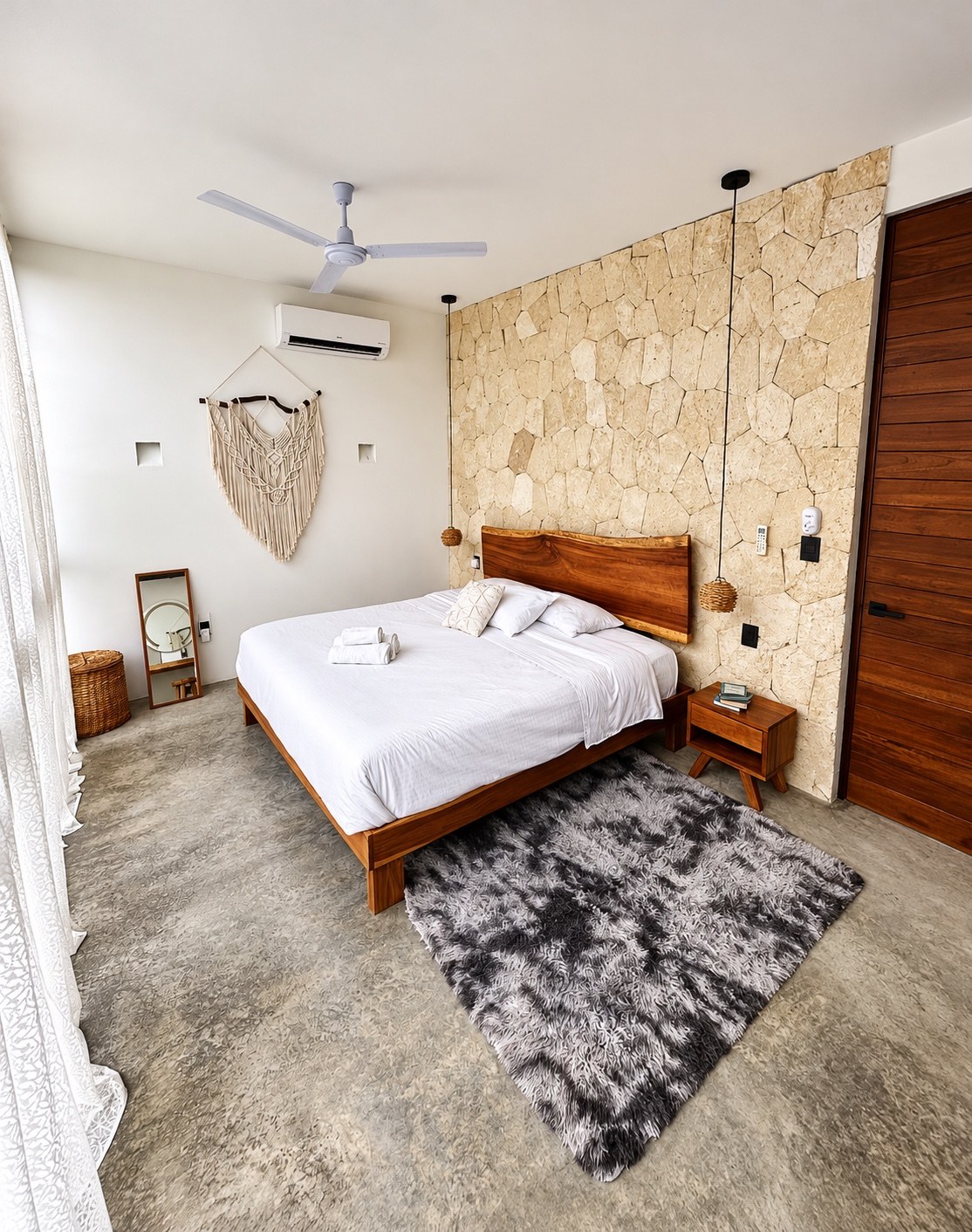 King bedroom with stone feature wall and large windows